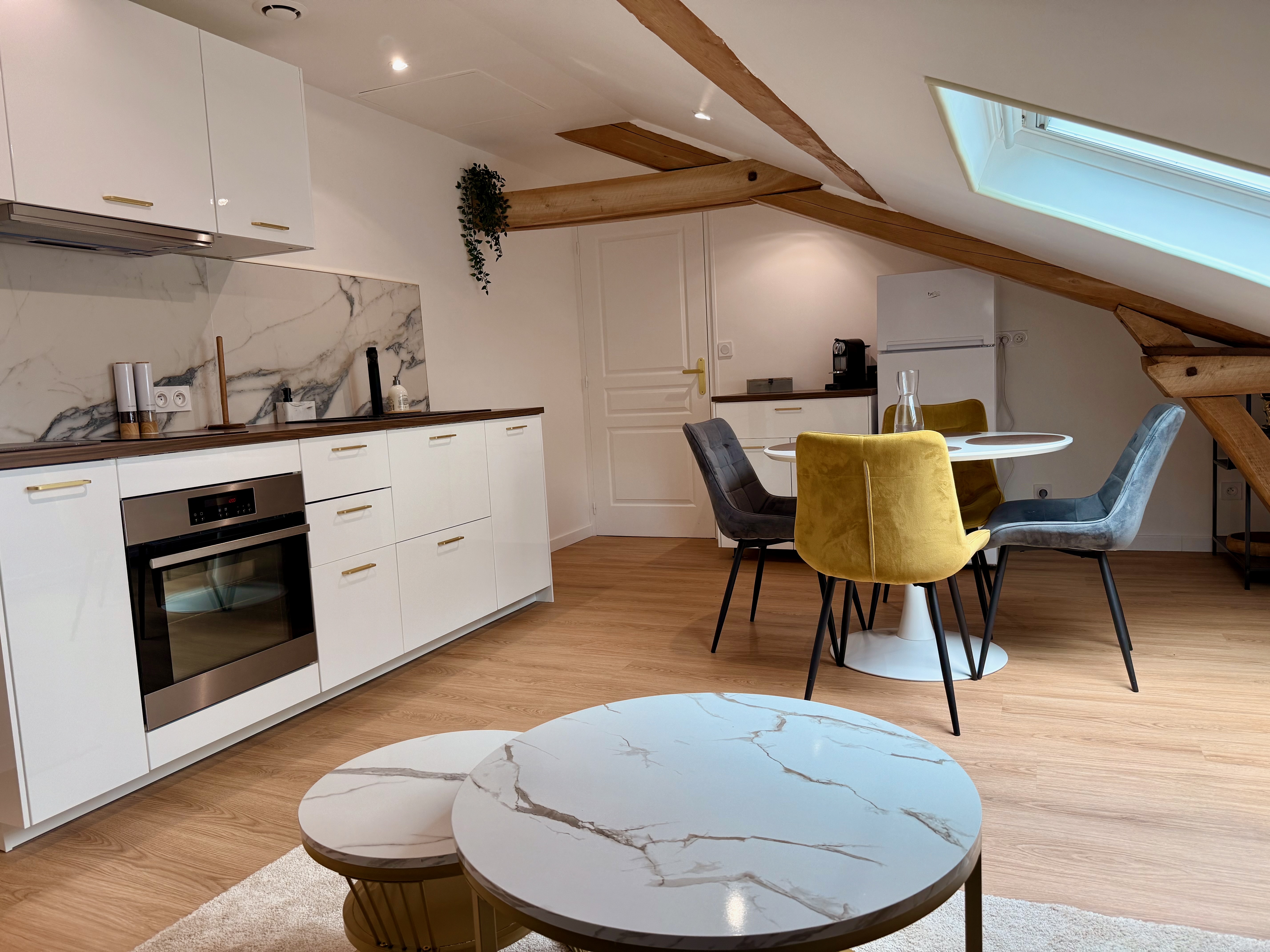 Cuisine ouverte avec espace repas mansardé, poutres apparentes et velux
